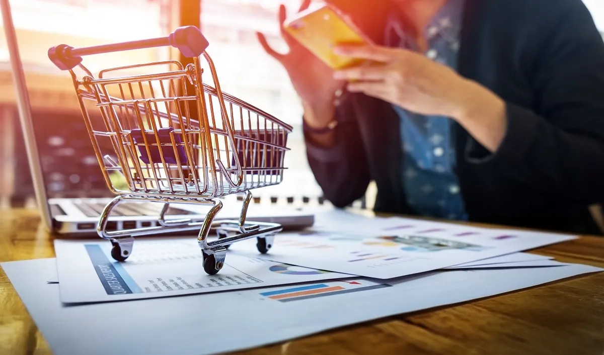 E-commerce - Carrinho de super-mercado perto de um computador
